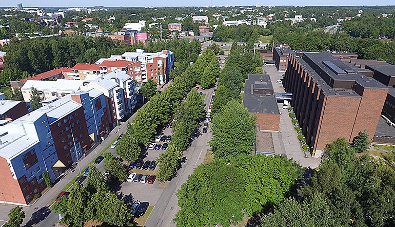 P-Hammasklinikka Helsinki, ilmakuvassa kerrostalorakennuksia ja parkkipaikka puiden keskellä