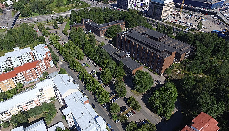P-Hammasklinikka Helsinki, ilmakuvassa kerrostalorakennuksia ja puita kaupunkimaisemassa