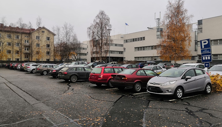 P-Joensuun virastotalo Joensuu, näkymä parkkialueelle 2, jossa on autoja ja taustalla liiketilarakennus