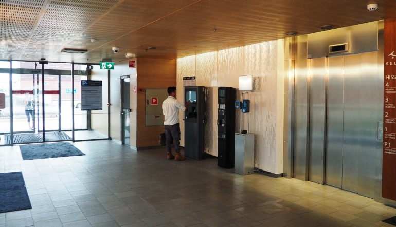 P-Kattoparkki Espoo, mies käyttää maksuautomaatteja sisäänkäynnin sisäpuolella