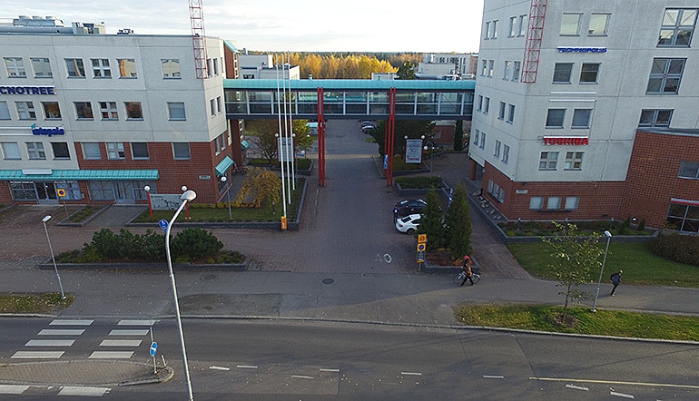 P-Kiinteisto Oy Hermia Tampere, ilmakuva sisäänajosta parkkialueelle kahden rakennuksen välistä, kävelysillan alta