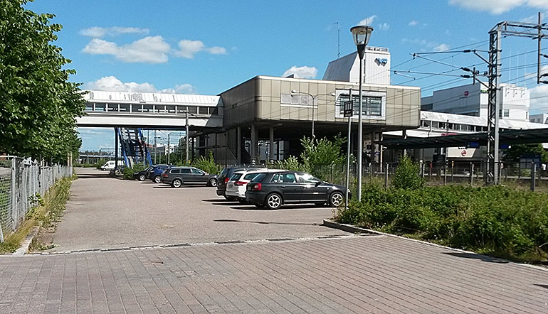P-Malmin asema Helsinki, asfaltoitu parkkipaikka juna-aseman ja ylikulkusiltojen vieressä
