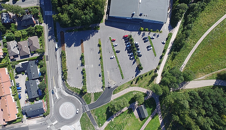 P-Paloheinän jäähalli Helsinki, ilmakuvassa asfaltoitu parkkipaikka, nurmikkoa ja puita, sekä hallin katto Paloheinässä