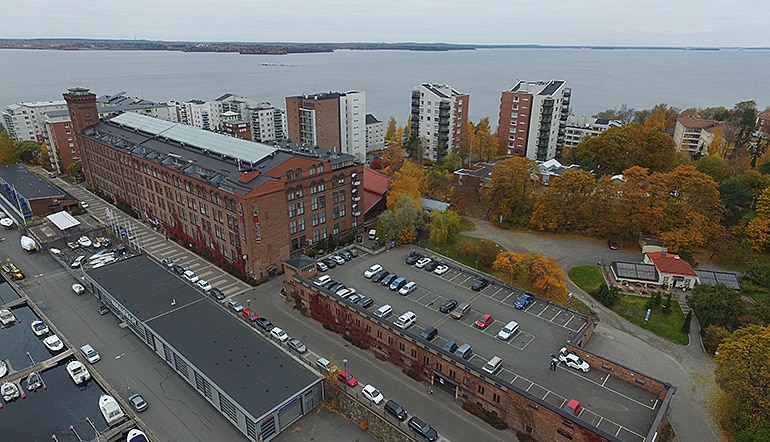 P-Tampereen kylpylä Tampere, ilmakuvassa parkkialue katolla ja näkymä hotellin ja muiden rakennusten yli meren suuntaan