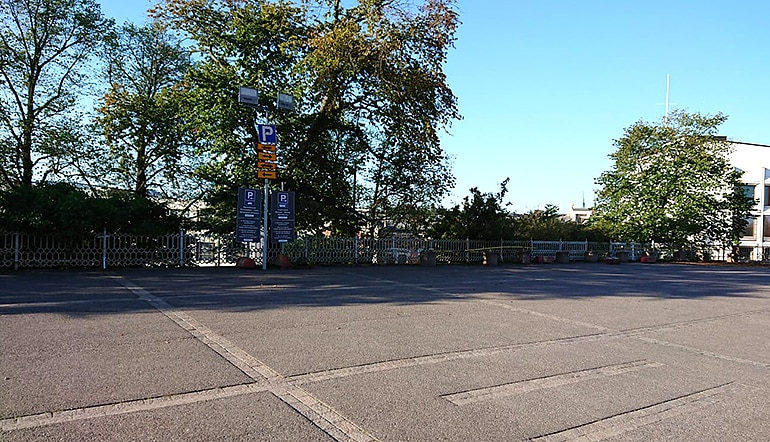 P-Uspenski Helsinki, asfaltoitu parkkipaikka jonka reunustalla on puita ja pensaita